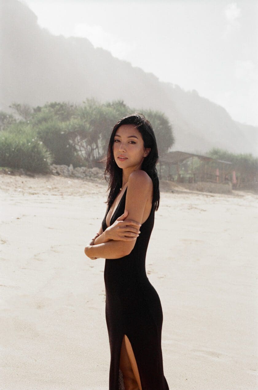 Side View of Model wearing Cinnamon Swimwear black Maxi Cover-Up Dress showing side split detailing